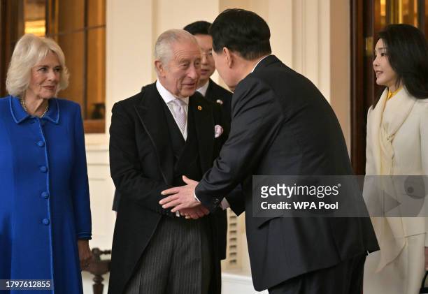 King Charles III shakes hands with South Korean President Yoon Suk Yeol, watched by Britain's Queen Camilla and South Korea's First lady Kim Keon Hee...