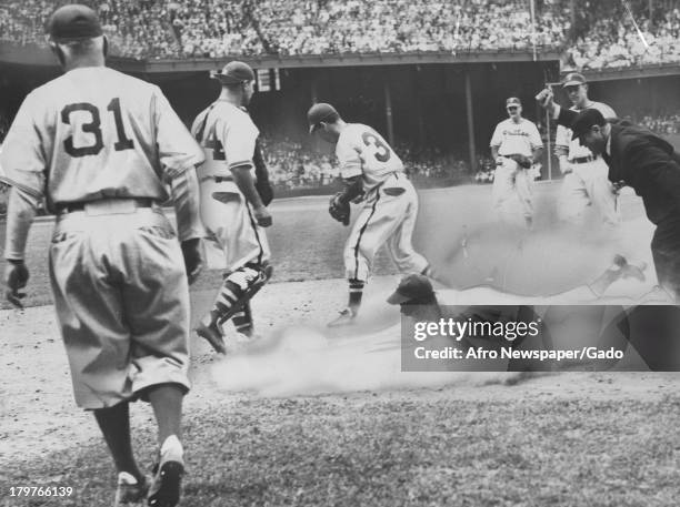 Trapped between first and second in the first game of a doubleheader with the Phillies in the Quaker City, American baseball player Jackie Robinson...