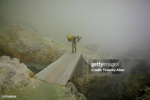 miner carriers sulfur blocks across bridge - sulphur stock pictures, royalty-free photos & images