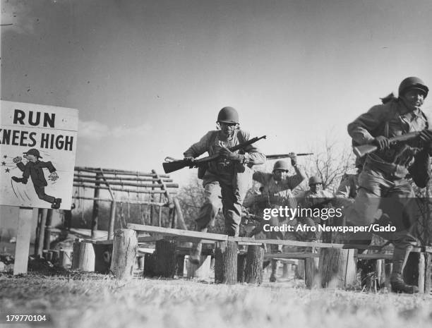 African-American soldiers in full gear and toting guns run obstacle course they constructed at Aberdeen Proving Grounds army base, Aberdeen,...