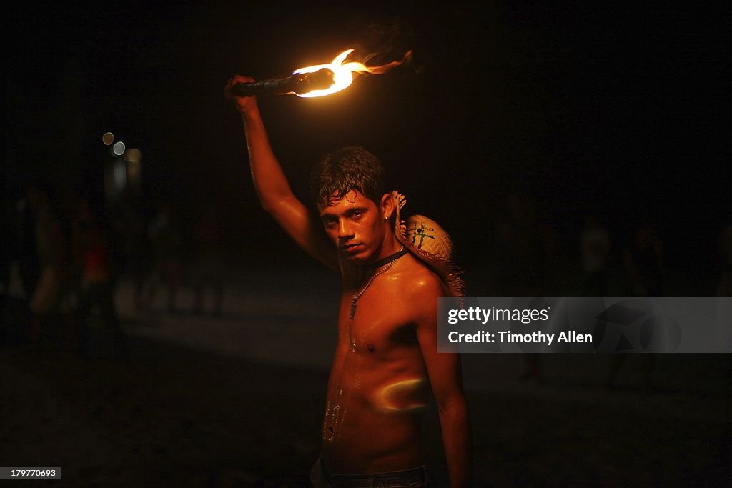 Amazonian man lit by red torchlight at night