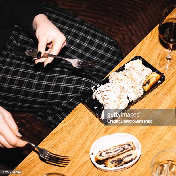 young woman holding forks while sitting by the table eating dessert - flash stock pictures, royalty-free photos & images