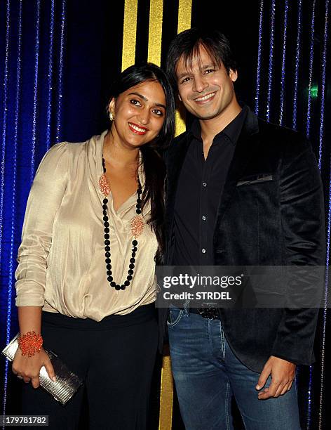 Indian Bollywood actor Vivek Oberoi with his wife pose during the 64th birthday celebrations for Indian Bollywood director Rakesh Roshan in Mumbai on...