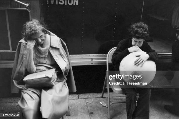 Boy blows up a large balloon next to a sleeping elderly woman, Lower Manhattan, New York City, 1979.