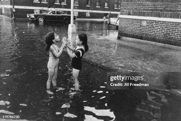 Two girls play in a flooded street in the South Bronx, New York City, 1975.