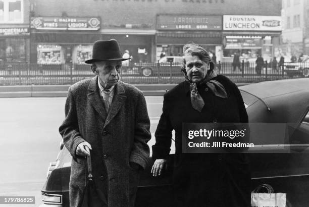 An elderly couple lean against a car on Delancey Street, New York City, 1966.