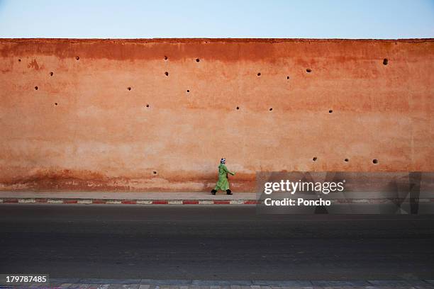 woman walking along a clay wall - barricade stockfoto's en -beelden