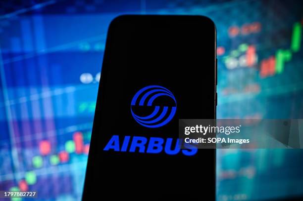 In this photo illustration, an Airbus logo is displayed on a smartphone with a line graph in the background.