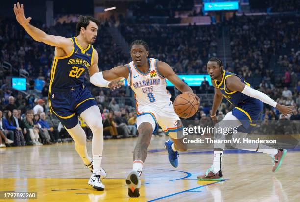Jalen Williams of the Oklahoma City Thunder drives to the basket between Jonathan Kuminga 00 and Dario Saric of the Golden State Warriors during the...