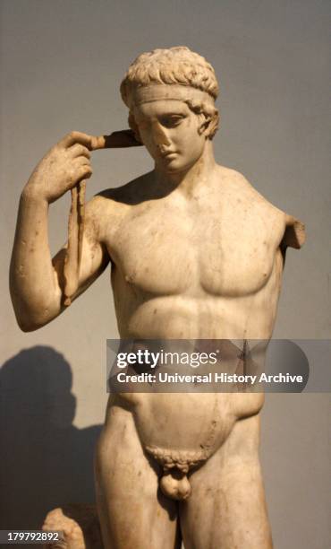 Roman statue of a victorious young athlete. 1st century AD. Remade from a Greek original of about 430 BC. The athlete shown tying a ribbon around his...