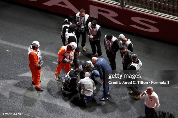 Track marshals and officials inspect an area of track near a drain as seen from the McLaren VISTA during practice ahead of the F1 Grand Prix of Las...