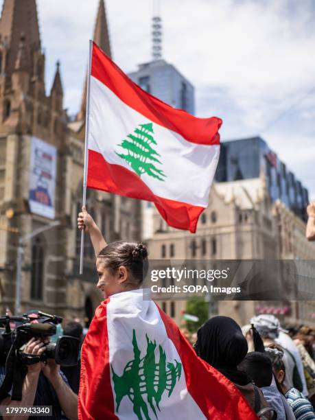 Young child with Palestinian flag facepaint holds and dons Lebanese flags in front of St. Paul's Cathedral during the protest. Hundreds of primary...