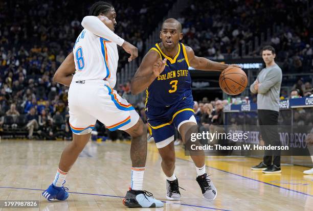 Chris Paul of the Golden State Warriors dribbles the ball while being guarded by Jalen Williams of the Oklahoma City Thunder during the third quarter...