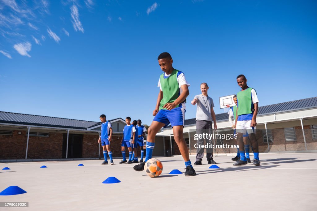 Schoolboys practice their soccer skills in the courtyard with their coach