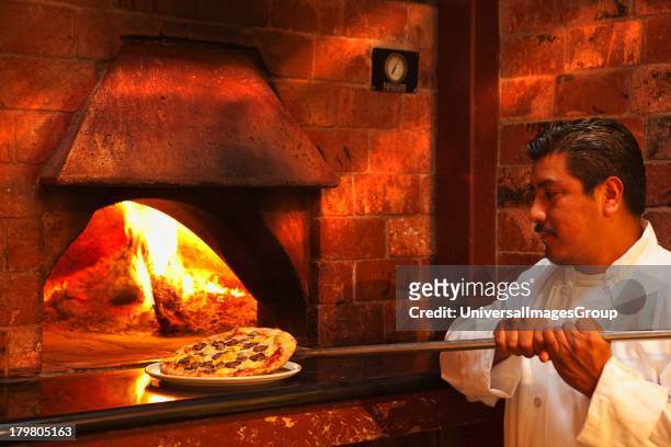 Quattro stagioni pizza, with mozzarella cheese, artichokes, mushrooms and sausage is pulled from the pizza oven, Trattoria Uliveto, Orcutt,...