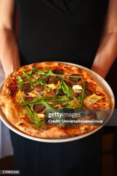 Quattro stagioni pizza, with mozzarella cheese, artichokes, mushrooms, sausage and arugula is served, Trattoria Uliveto, Orcutt, California.