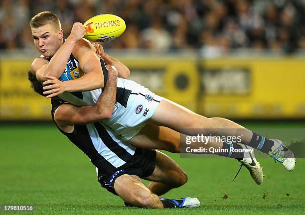 Oliver Wines of the Power handballs whilst being tackled by Steele Sidebottom of the Magpies during the Second AFL Elimination Final match between...