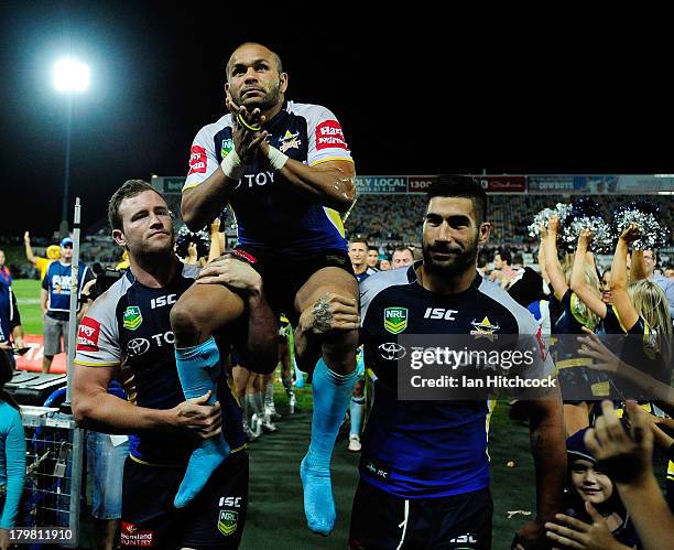 Matthew Bowen of the Cowboys is chaired from the ground by Gavin Cooper and James Tamou at the end of the round 26 NRL match between the North...