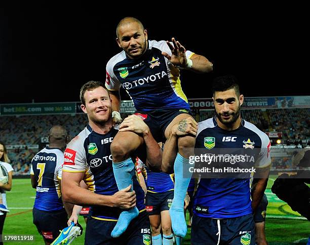 Matthew Bowen of the Cowboys is chaired from the ground by Gavin Cooper and James Tamou at the end of the round 26 NRL match between the North...