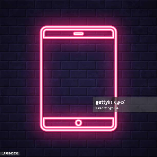 tablet pc. glowing neon icon on brick wall background - interactive display wall stock illustrations