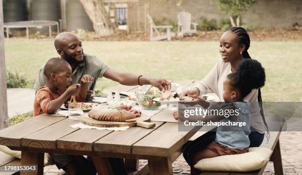 cibo, picnic e una famiglia nera nel giardino di casa insieme per la salute, la dieta o la nutrizione. amore, sorriso o felice con una madre, un padre e bambini che mangiano a tavola all'aperto nel cortile o nel parco - african travel smile foto e immagini stock