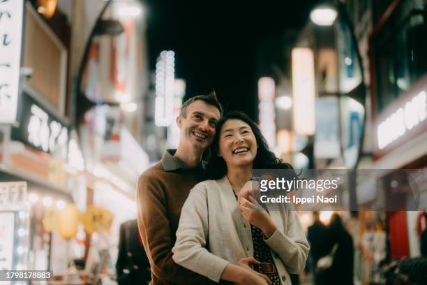 couple enjoying tokyo at night - oriente foto e immagini stock