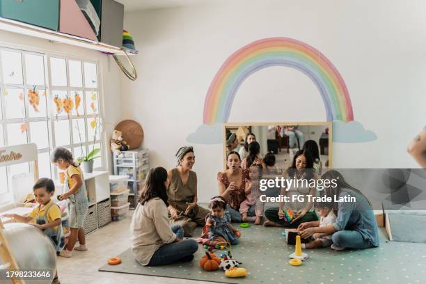 mothers talking in a support group at playroom - peuterschool gebouw stockfoto's en -beelden