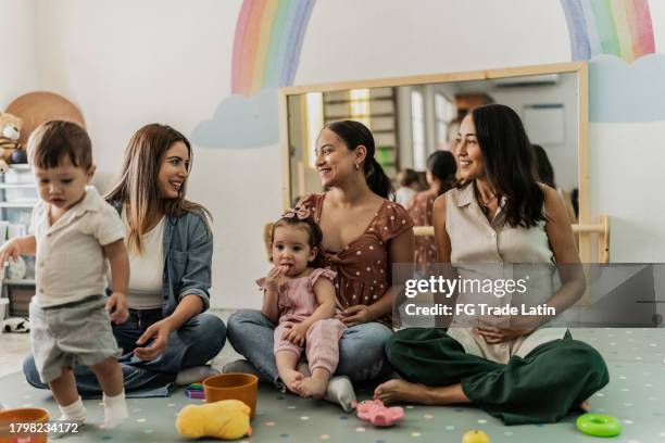 mothers talking while their babies playing in a support group therapy on a playroom - toddler learning stock pictures, royalty-free photos & images