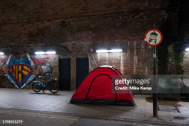 Tent of a homeless person underneath old railway bridges outside Waterloo station at night on 15th November 2023 in London, United Kingdom. The...