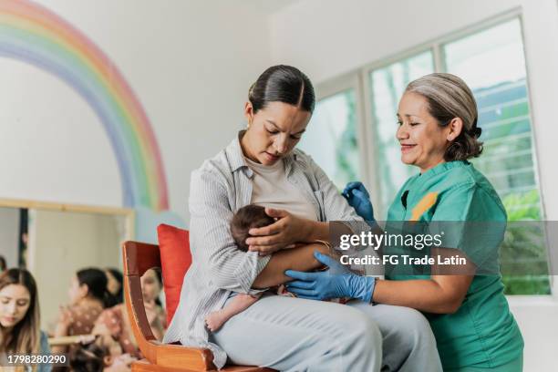 mujer madura aprendiendo a amamantar a su hija en grupo de apoyo - comadrona fotografías e imágenes de stock