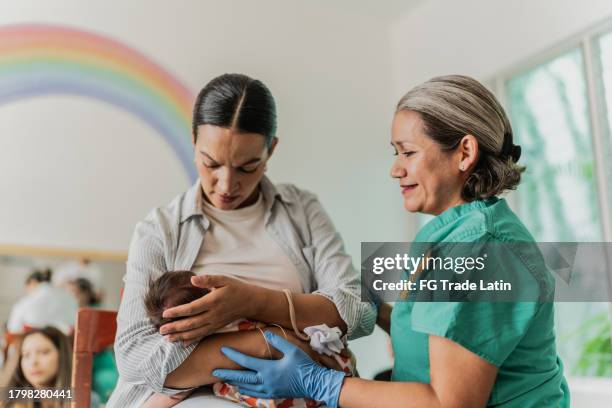 mujer madura aprendiendo a amamantar a su hija en grupo de apoyo - comadrona fotografías e imágenes de stock