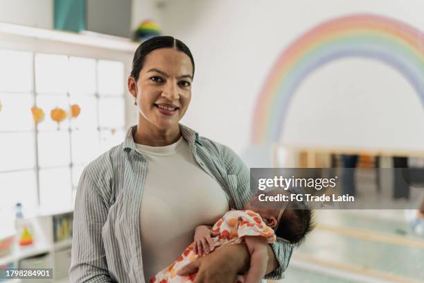 portrait of a mature mother holding her sleeping baby girl in the playroom - lullaby stock pictures, royalty-free photos & images