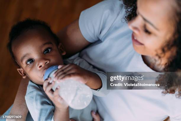 mother feeds her baby boy with baby milk. - garrafa de leite imagens e fotografias de stock