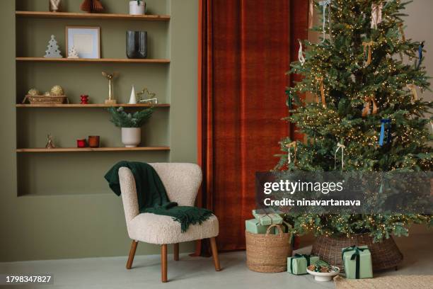 illuminated christmas tree and wrapped gifts in a stylish living room decorated for christmas - simple living stock pictures, royalty-free photos & images