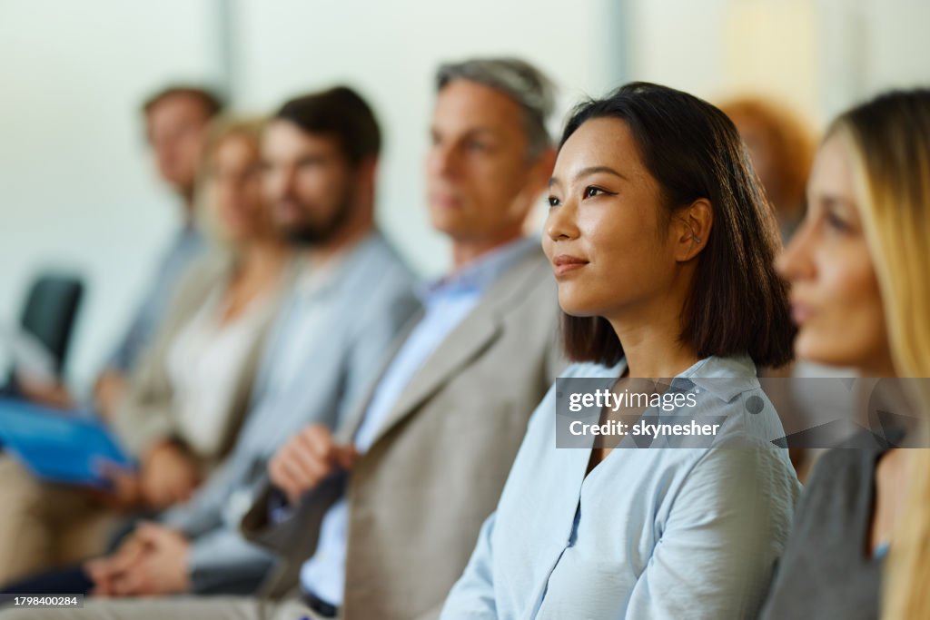 Lächelnde chinesische Geschäftsfrau, die mit ihren Kollegen an einem Seminar teilnimmt.