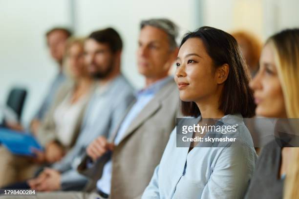 smiling chinese businesswoman attending a seminar with her colleagues. - corporate training stock pictures, royalty-free photos & images