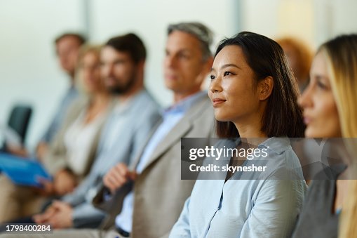 Smiling Chinese businesswoman attending a seminar with her colleagues. Smiling Chinese businesswoman attending a seminar with her colleagues.