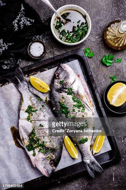 grilled dorado with herbs on a platter and baked potatoes - 魚類 ストックフォトと画像