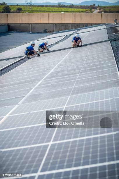 team of three engineers installing solar panels on roof - united nations framework convention on climate change stock pictures, royalty-free photos & images