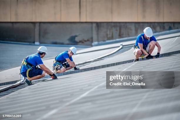 team of three engineers installing solar panels - rooftop stock pictures, royalty-free photos & images