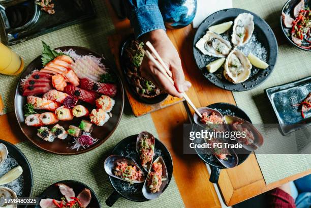 close-up of a person using chopsticks to pick japanese food at sushi bar - japanese food stock pictures, royalty-free photos & images