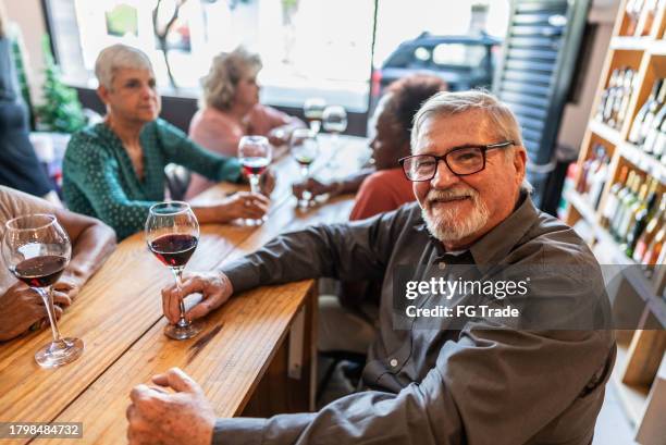 porträt eines glücklichen älteren mannes in einem restaurant mit freunden - weinbar stock-fotos und bilder