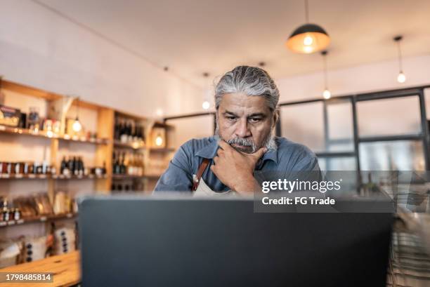 propietario de un negocio preocupado que usa una computadora portátil - vendedor del mercado fotografías e imágenes de stock
