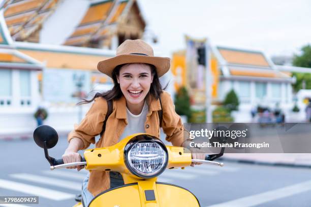 young woman riding on motorbike moped scooter in city street - moped stock-fotos und bilder