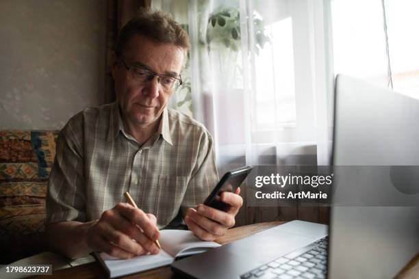senior man writing down verification code to protect himself from fraud. - forgot password stock pictures, royalty-free photos & images