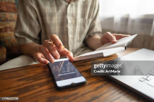 senior man writing down verification code to protect himself from fraud. - report crime stock pictures, royalty-free photos & images