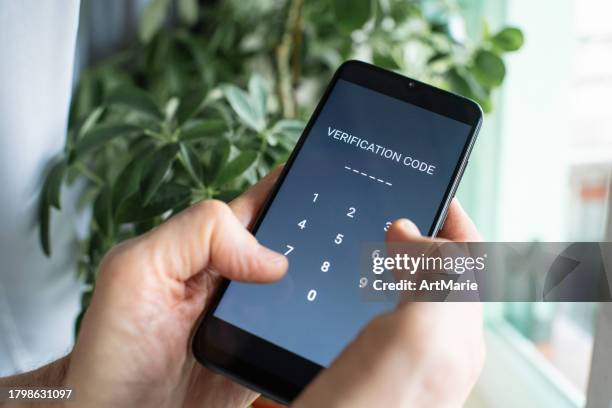 serious senior man at home entering verification code in smartphone, fraud prevention concept. - digitale authenticatie stockfoto's en -beelden