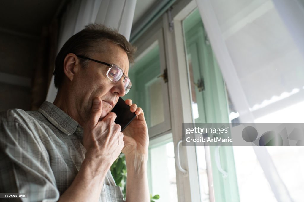 Senior man in confusion talking by phone at home
