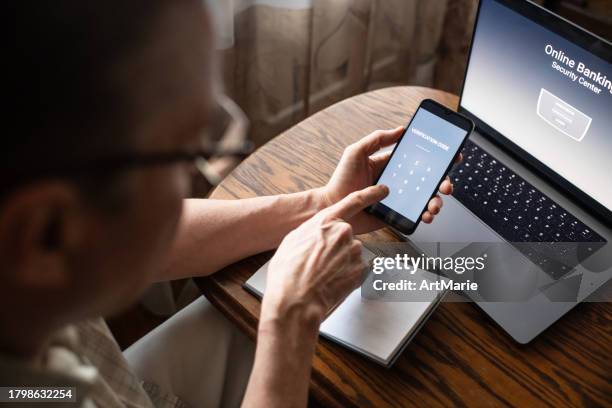 serious senior man at home entering verification code in smartphone, fraud prevention concept. - fraud prevention stock pictures, royalty-free photos & images