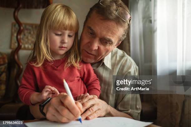 child with grandfather spending time together at home - granddaughter stock pictures, royalty-free photos & images